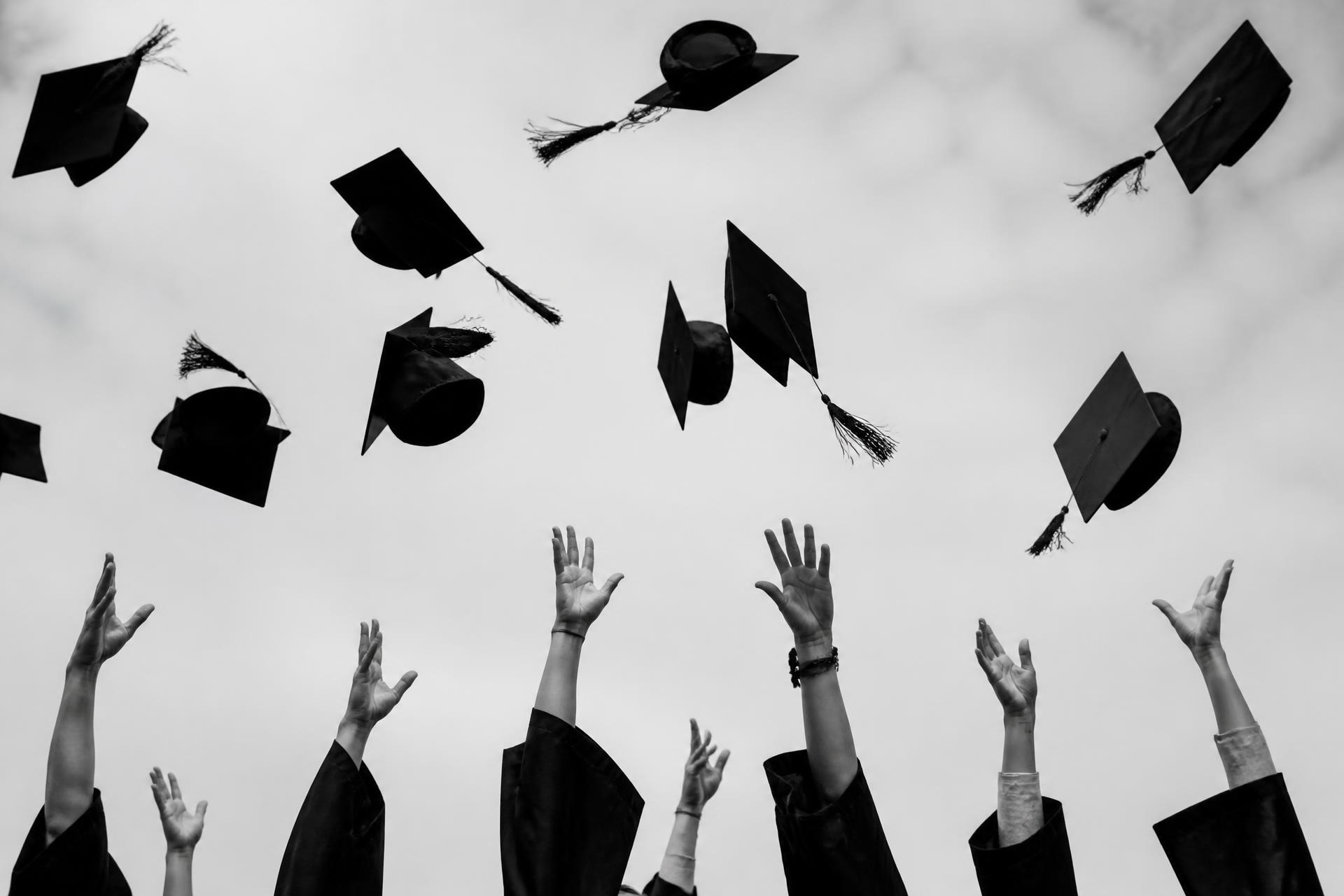 Graduation caps flying into the air as students celebrate together